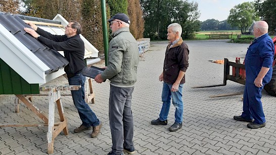 Harrie Nobbenhuis kijkt of de dakpannen passen op het bouwwerk. Henk Koorman, Gerard Grootelaar en Theo Lohuis kijken toe. Foto: Anton Schrijver.